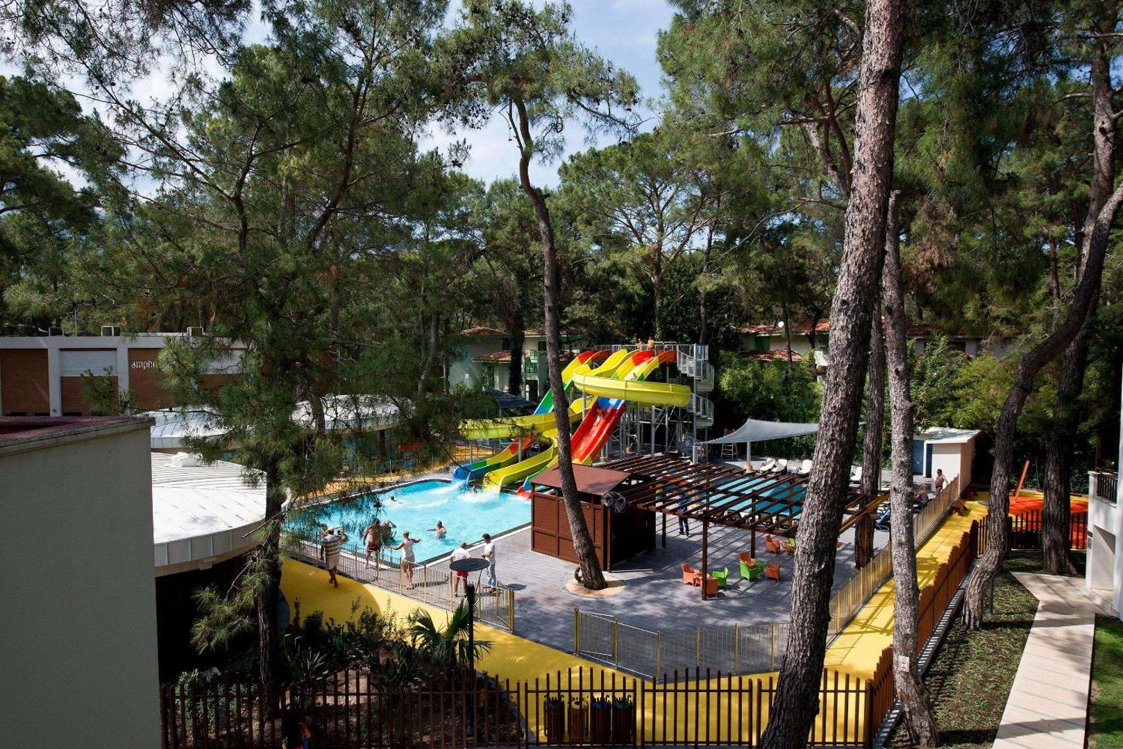 Seven Seas Hotel Life akvaparks ar krāsainiem ūdens slidkalniņiem un baseinu, ko ieskauj augstas priedes un sauļošanās terase