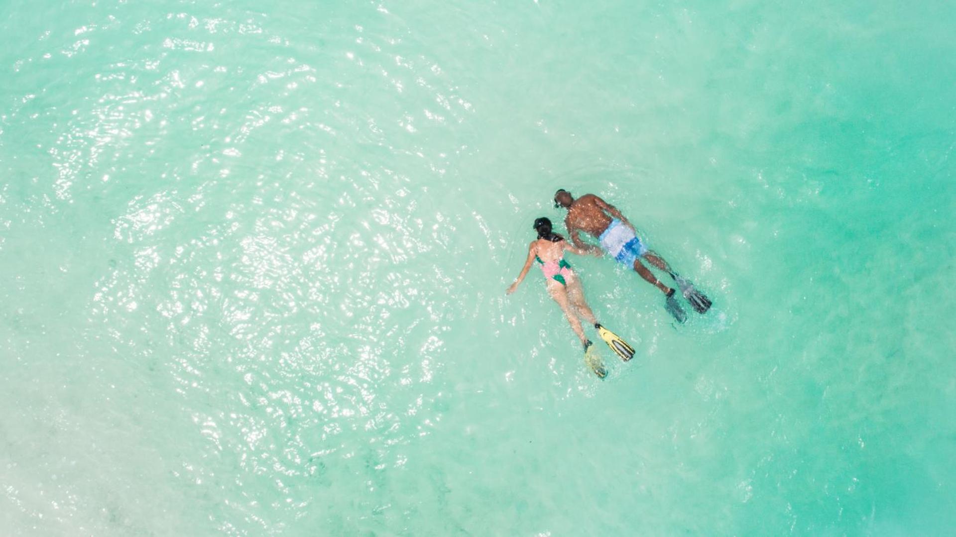 Pāris nirst ar maskām un spurām Veligandu Maldives Resort Island tirkīzzilajā okeāna ūdenī virs koraļļu rifa