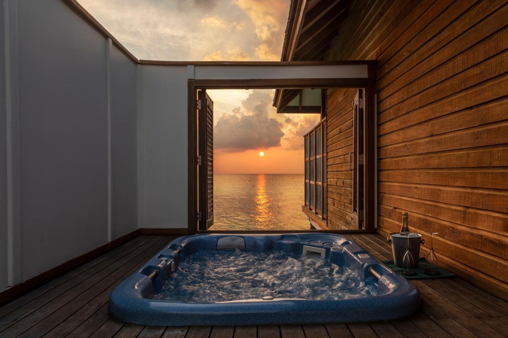 Veligandu Maldives Resort Island ūdens villas terase ar burbuļvannu un šampanieti saulrieta laikā Maldivu salās