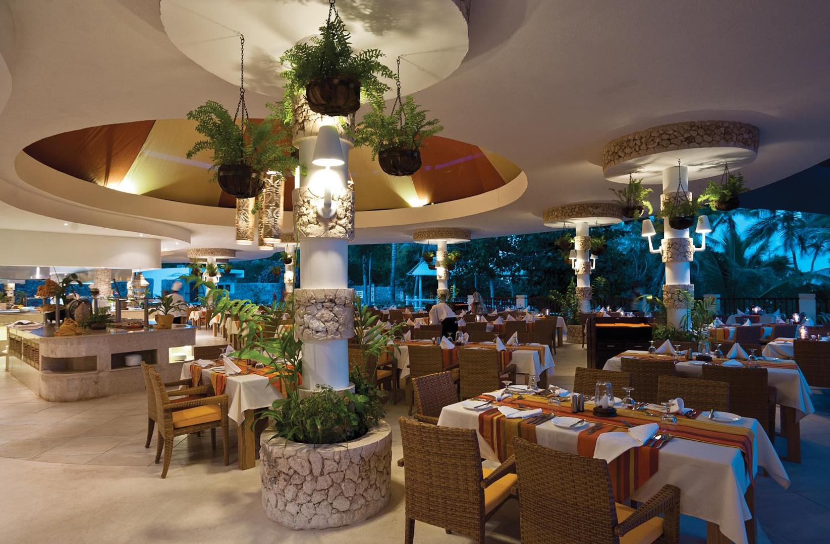 Leopard Beach Resort & Spa restorāna interjers vakarā ar klātiem galdiem, akmens kolonnām un dekoratīviem augiem podos