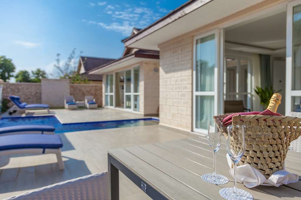 Leopard Beach Resort & Spa luksusa villas terase ar privātu baseinu, sauļošanās krēsliem un galdu, uz kura novietots šampanietis