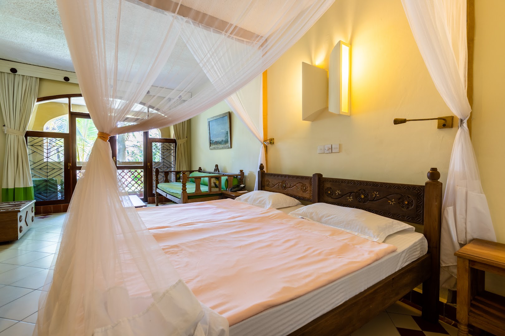 Severin Sea Lodge numurs ar kokgriezuma gultas galvgali, rozā gultasveļu un dīvānu pie loga Kenijas kūrortā