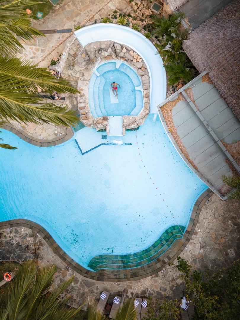 Severin Sea Lodge viesnīcas baseina skats no augšas ar mākslīgo klinti un atpūtas zonu tropu dārzā