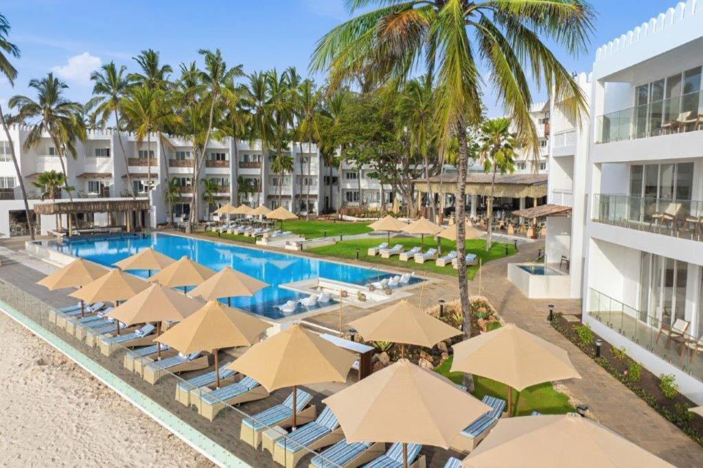 Bamburi Beach Hotel teritorijas skats no augšas ar baseinu, saulessargiem, palmām un viesnīcas korpusiem pie pludmales