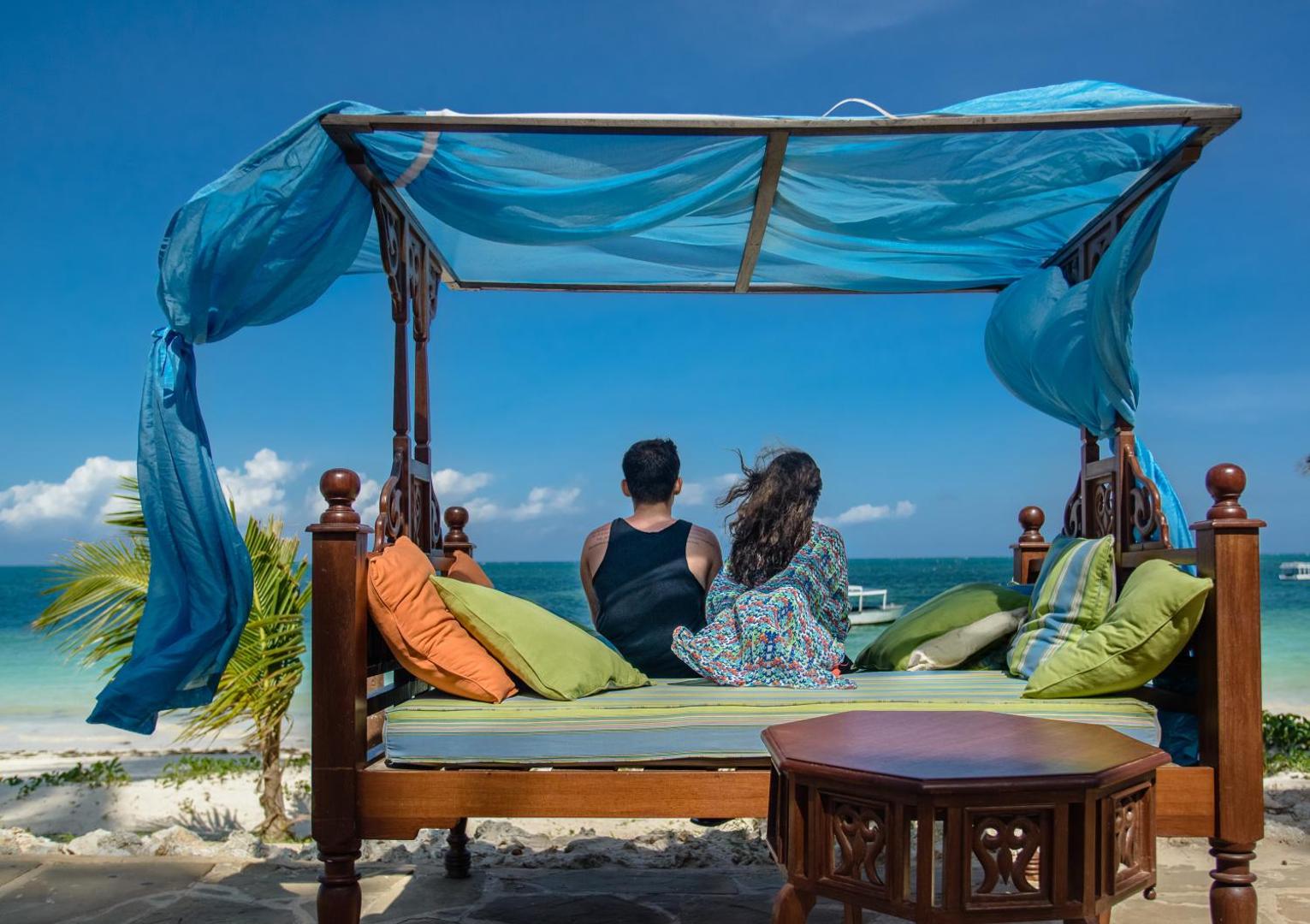 Sarova White Sands Beach Resort & Spa pludmales atpūtas vieta ar krāsainiem spilveniem un skatu uz Indijas okeānu saulainā dienā