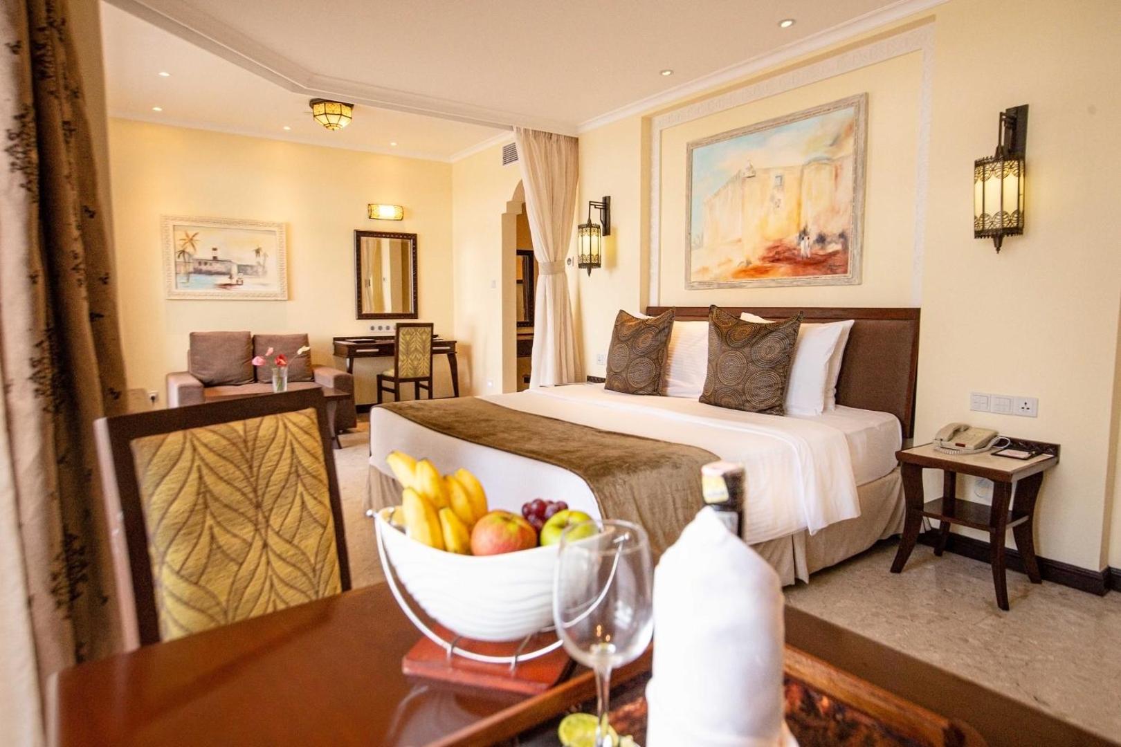 Sarova White Sands Beach Resort & Spa mājīgs numurs ar lielu gultu, atpūtas zonu un augļu trauku priekšplānā Mombasā, Kenijā