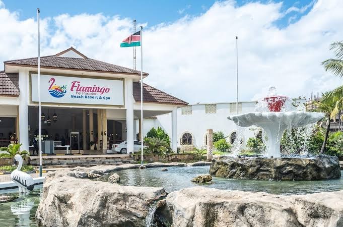 PrideInn Flamingo Beach Resort & Spa ieeja ar strūklaku un viesnīcas logo pie galvenās ēkas Kenijā