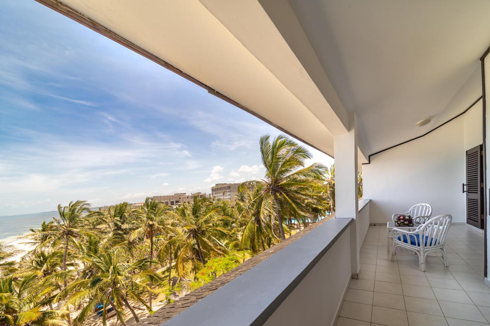 Skats no PrideInn Flamingo Beach Resort & Spa numura balkona uz palmu dārzu un Indijas okeāna piekrasti Mombasā
