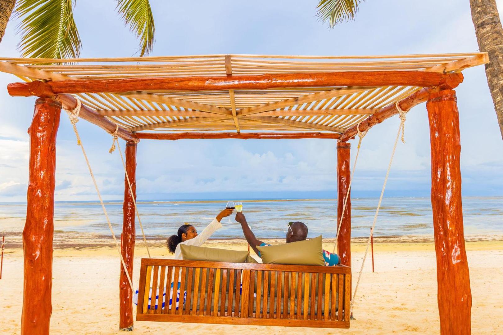 PrideInn Flamingo Beach Resort & Spa pāris bauda dzērienus koka lapenē pludmalē ar skatu uz Indijas okeānu