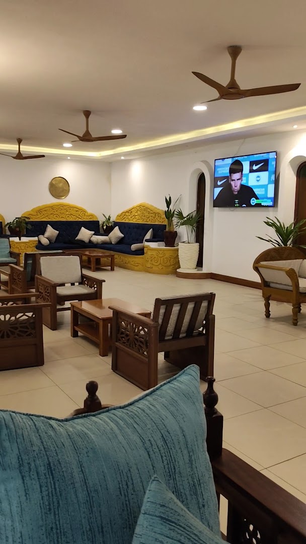 PrideInn Flamingo Beach Resort & Spa viesnīcas lobby zona ar koka mēbelēm, ziliem dīvāniem un griestu ventilatoriem