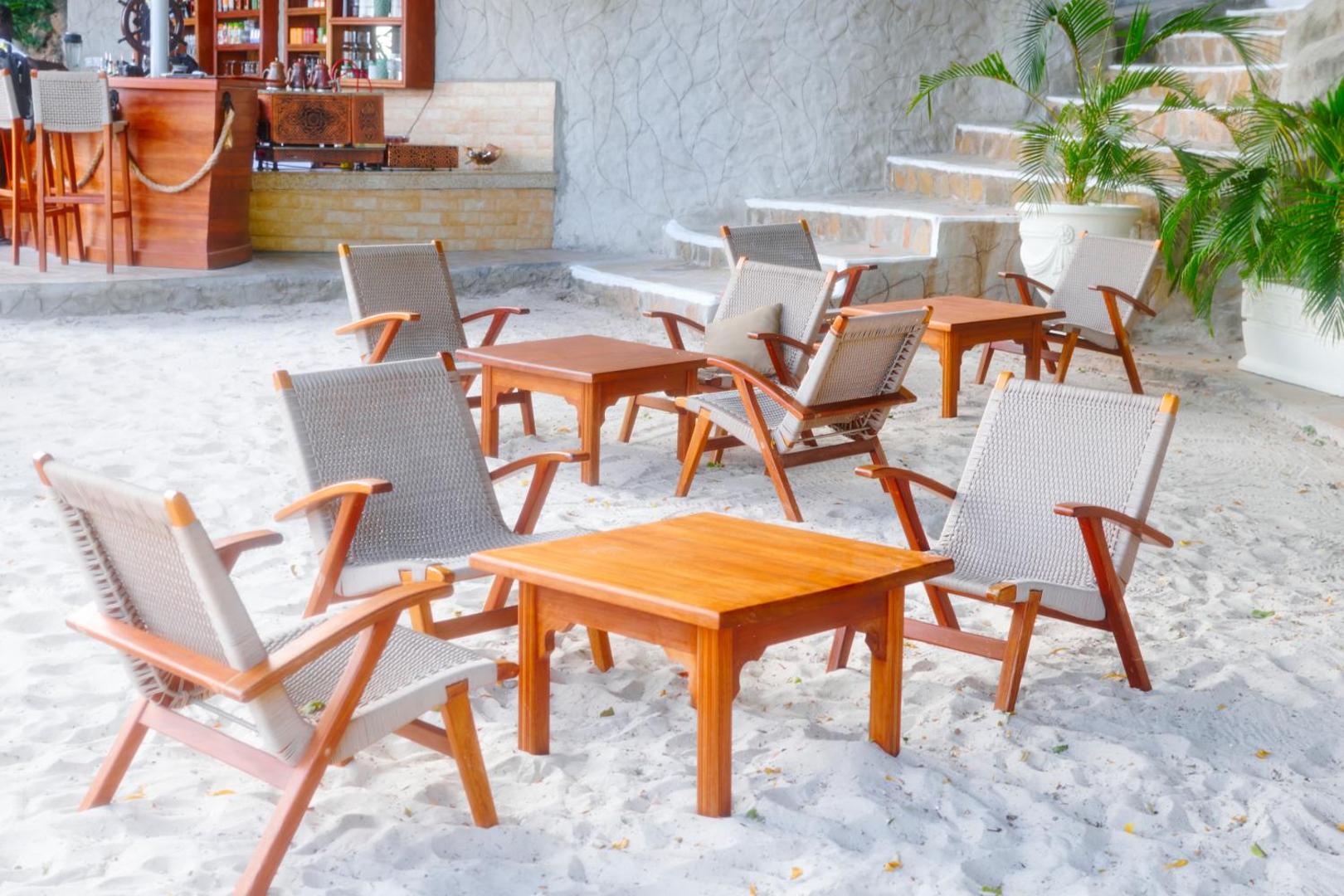 PrideInn Flamingo Beach Resort & Spa pludmales bāra terase ar koka galdiem un krēsliem baltās smiltīs piekrastē