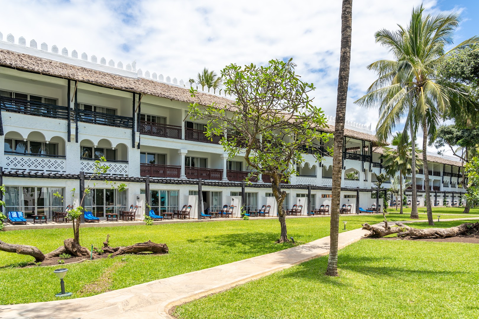 Southern Palms Beach Resort arhitektūra ar tradicionāliem jumtiem un koptu dārzu, kurā izvietoti gājēju celiņi un atpūtas krēsli