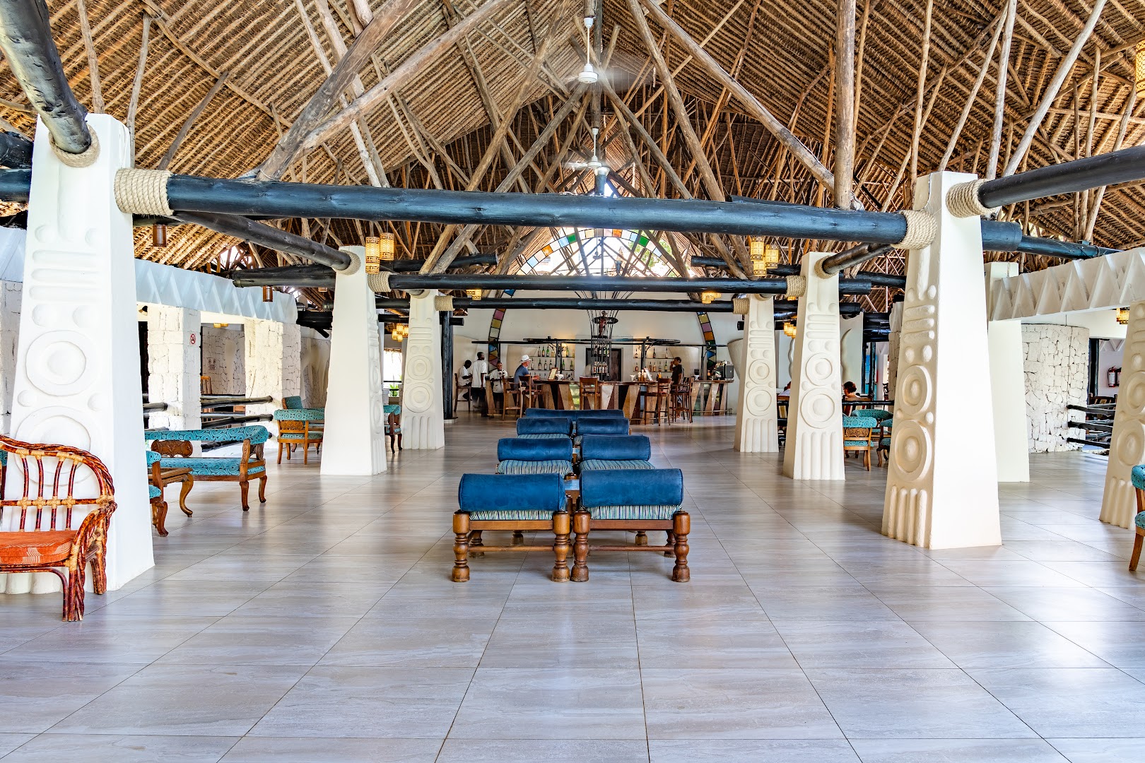Southern Palms Beach Resort plašā atpūtas halle ar augstiem salmu griestiem, koka sijām un zilām mēbelēm piekrastē