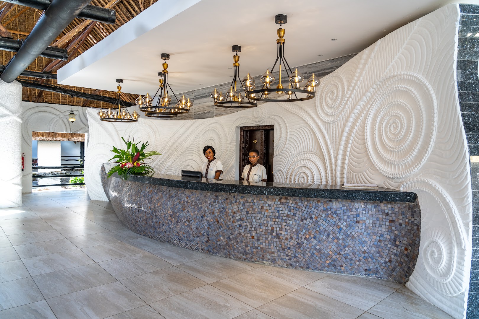 Southern Palms Beach Resort recepcijas zona ar unikālu rakstainu sienas dekoru, modernām lustrām un mozaīkas flīžu leti Kenijā