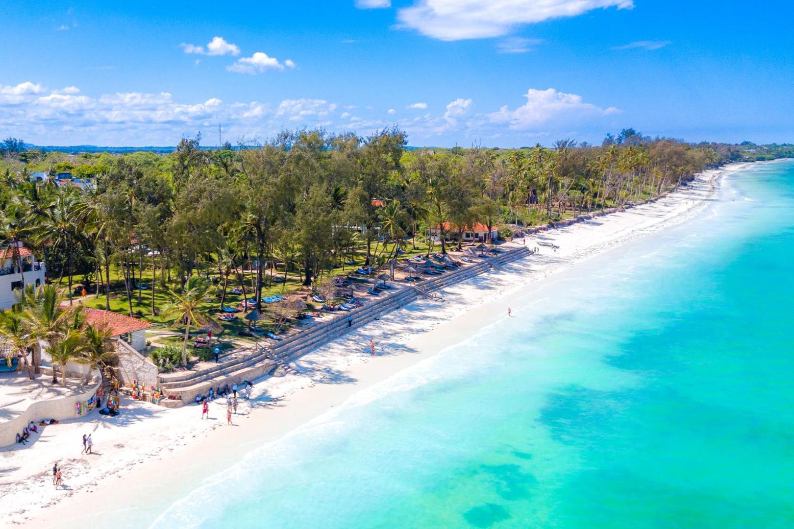 Diani Sea Resort viesnīcas teritorija no putna lidojuma — balto smilšu pludmale, tirkīza ūdens, palmas un atpūtas zona piekrastē