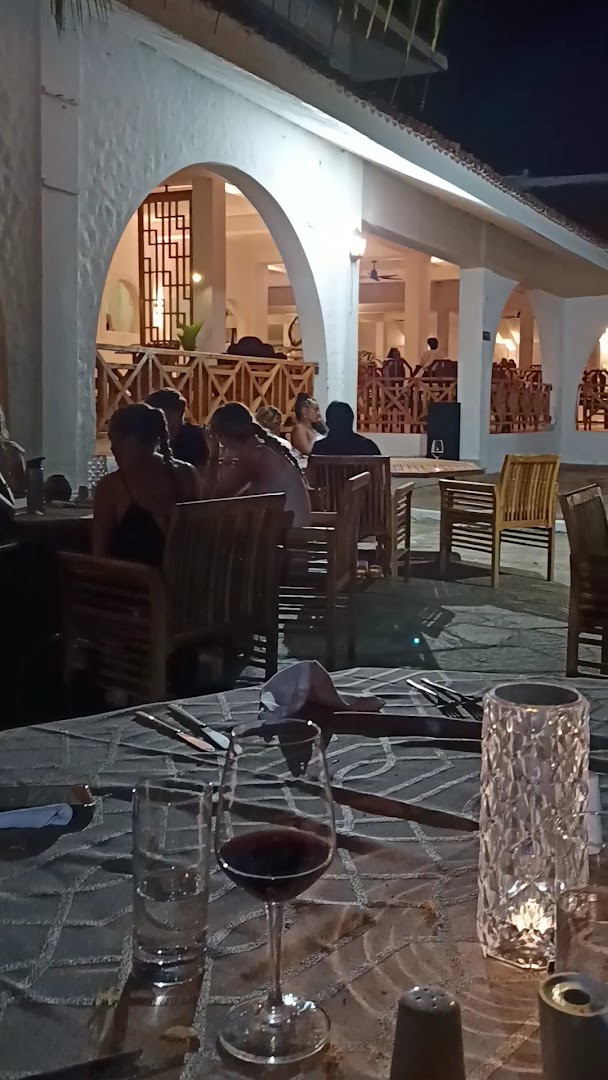 Diani Sea Resort restorāna āra terase vakarā — viesi bauda vakariņas pie galdiņiem ar vīnu un svecēm Kenijas piekrastē