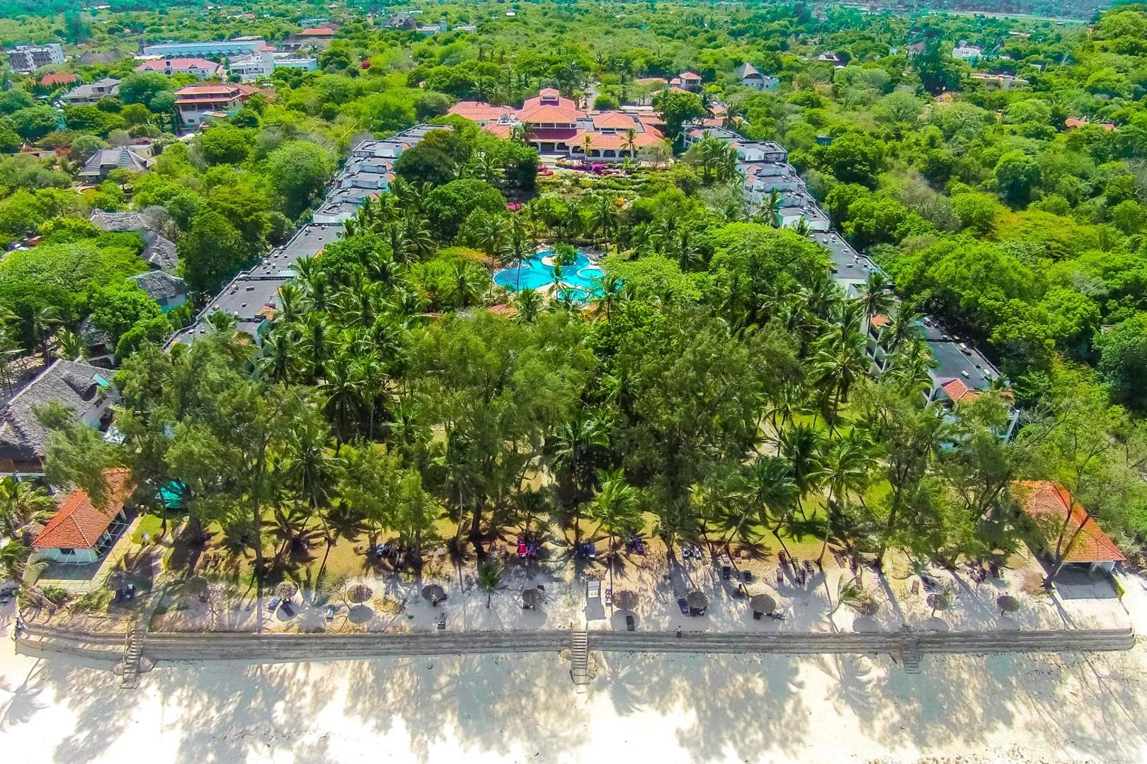 Diani Sea Resort aerofoto uzņēmums no putna lidojuma Kenijā — viesnīcas komplekss ar baseinu, palmu dārzu un balto smilšu pludmali