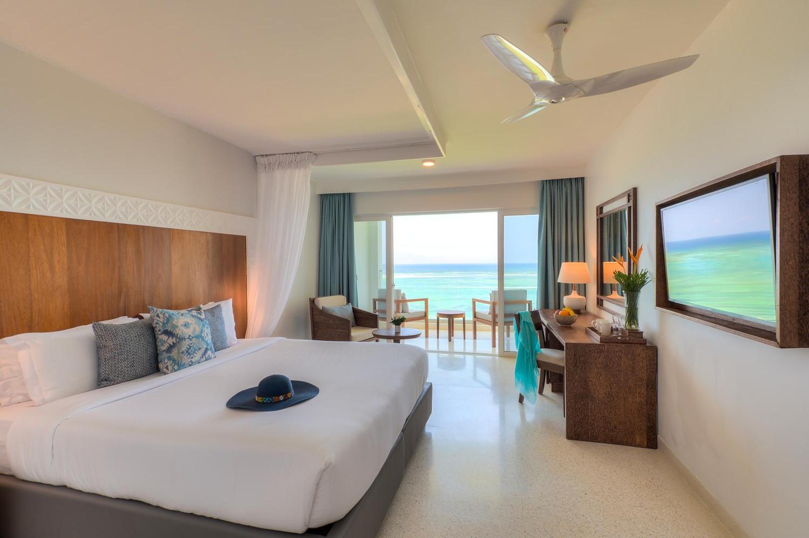 Gaišs Diamond Leisure Beach & Golf Resort viesnīcas numurs ar lielu gultu, koka mēbelēm un panorāmas skatu uz okeānu