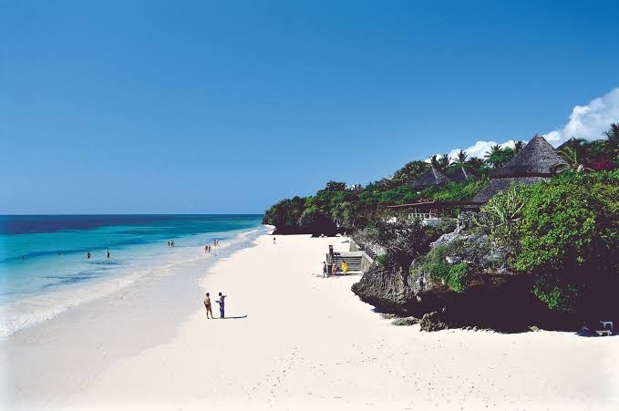 Diamond Leisure Beach & Golf Resort skats no augšas uz balto smilšu pludmali, tirkīza ūdeni un viesnīcas bungalo Zanzibārā