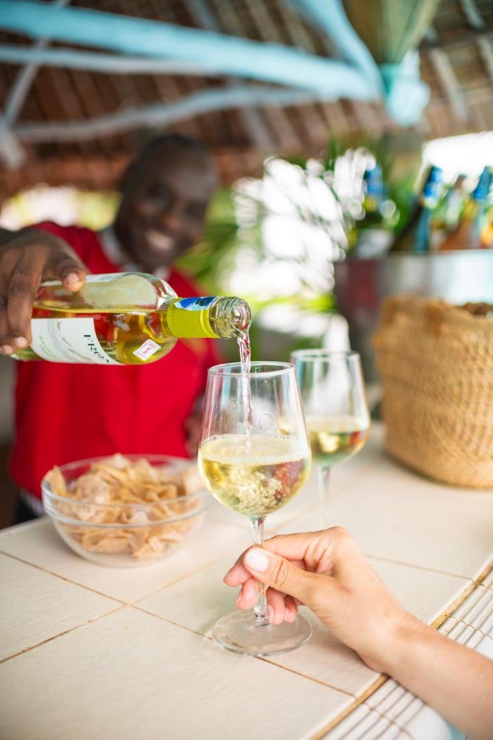 Diamond Leisure Beach & Golf Resort bārmenis lej vīnu glāzē pie bāra letes Kenijas piekrastē — viesmīlīga apkalpošana un atspirdzinoši dzērieni