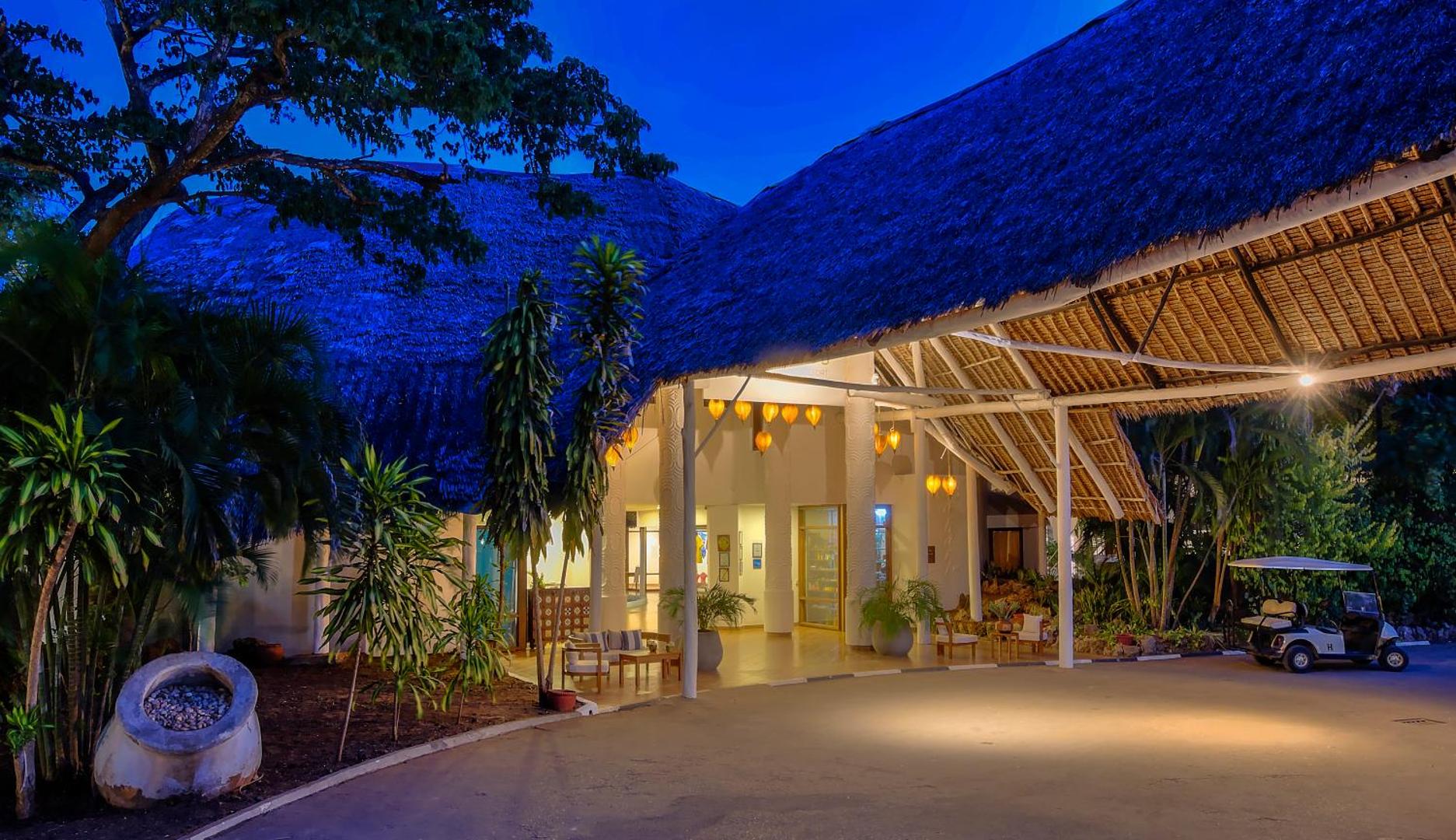 Diamond Leisure Beach & Golf Resort lobby ieeja vakarā ar tradicionālu jumtu, siltu apgaismojumu un viesnīcas transportu