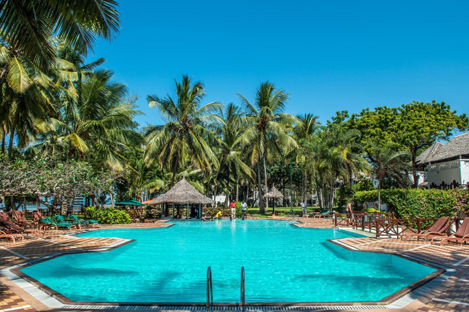 Serena Beach Resort & Spa āra baseins ar palmām un sauļošanās krēsliem Mombasas piekrastē, Kenijā — skats uz atpūtas zonu