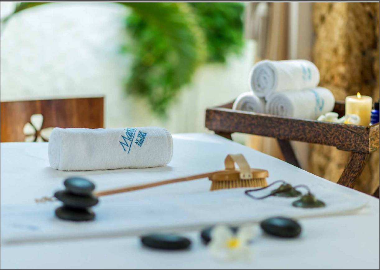 Serena Beach Resort & Spa spa procedūru galds ar dvieļiem, masāžas akmeņiem un aromātiskām svecēm relaksējošā vidē