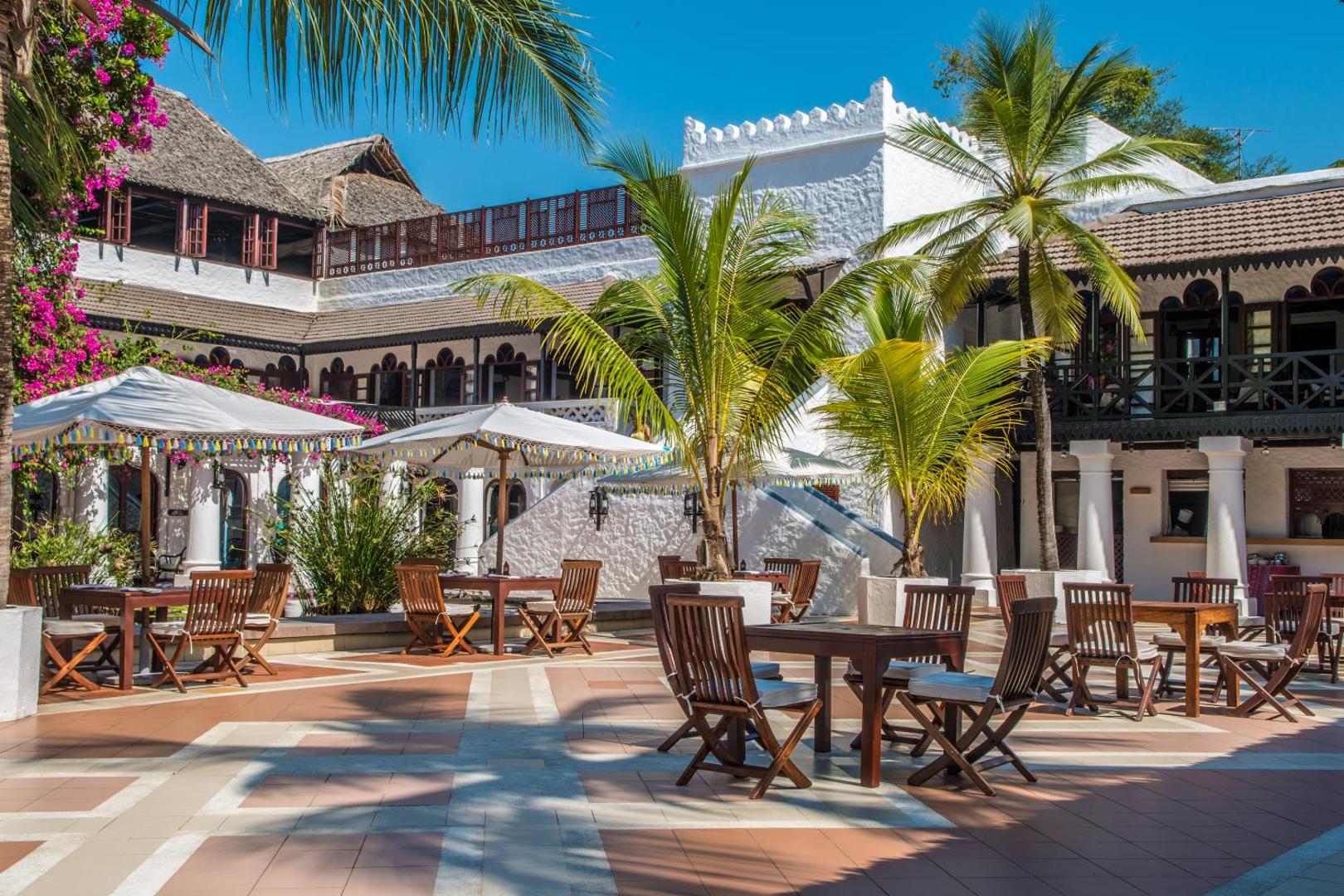 Serena Beach Resort & Spa viesnīcas arhitektūra ar baltām mūra sienām, koka balkoniem un tropu dārzu Mombasā