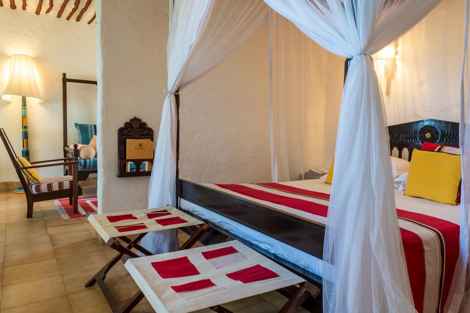 Serena Beach Resort & Spa numurs ar baldahīna gultu, tradicionāliem audumiem un atpūtas krēslu Mombasas kūrortā