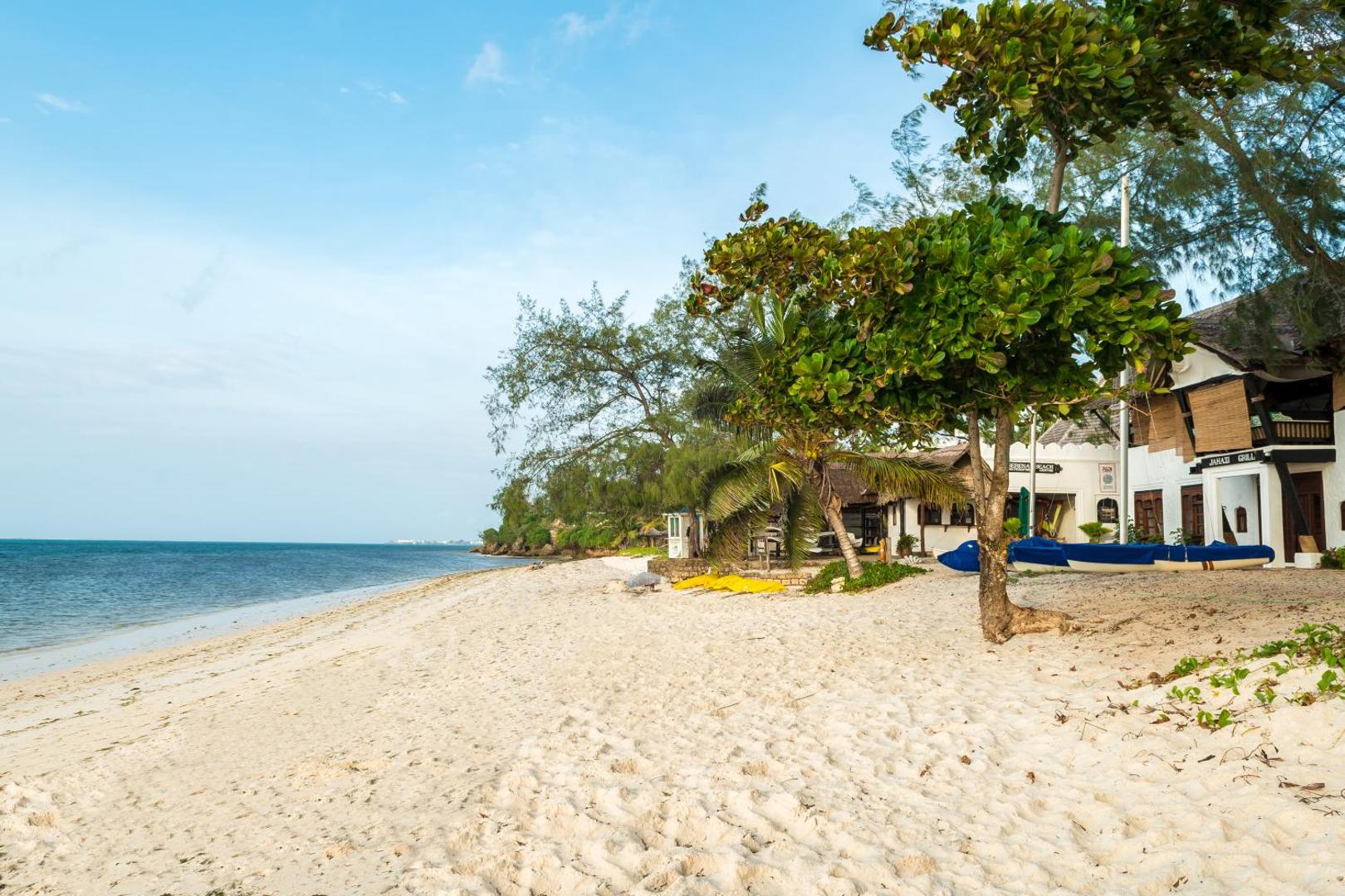 Serena Beach Resort & Spa privātā smilšu pludmale pie Indijas okeāna ar palmām un viesnīcas ēkām Mombasas piekrastē