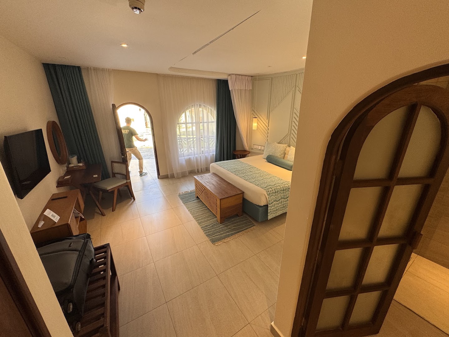 Gaišs Neptune Palm Beach Boutique Resort & Spa viesnīcas numurs ar lielu gultu, darba zonu un ieeju no dārza puses.
