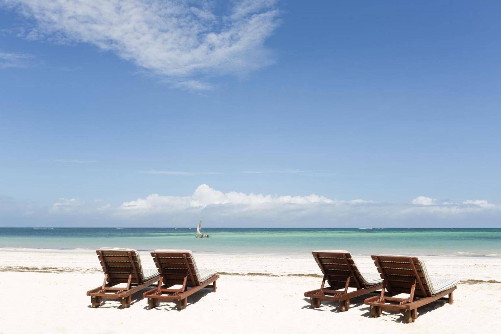 Koka sauļošanās krēsli Neptune Palm Beach Boutique Resort & Spa privātajā pludmalē Zanzibārā ar skatu uz Indijas okeānu.