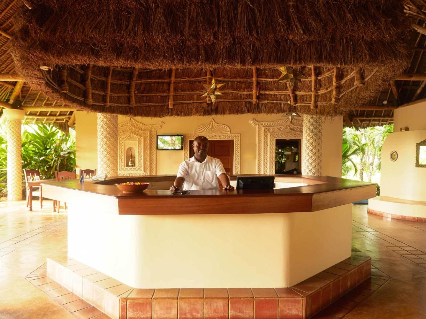 Neptune Palm Beach Boutique Resort & Spa viesnīcas recepcijas zona ar tradicionālu niedru jumtu un koka apdari Zanzibārā