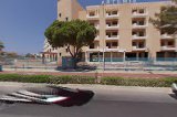 Maris Grand Waterpark Resort viesnīcas ieeja un fasāde dienas laikā — piebraucamais ceļš, koki un daudzstāvu ēka Grieķijā