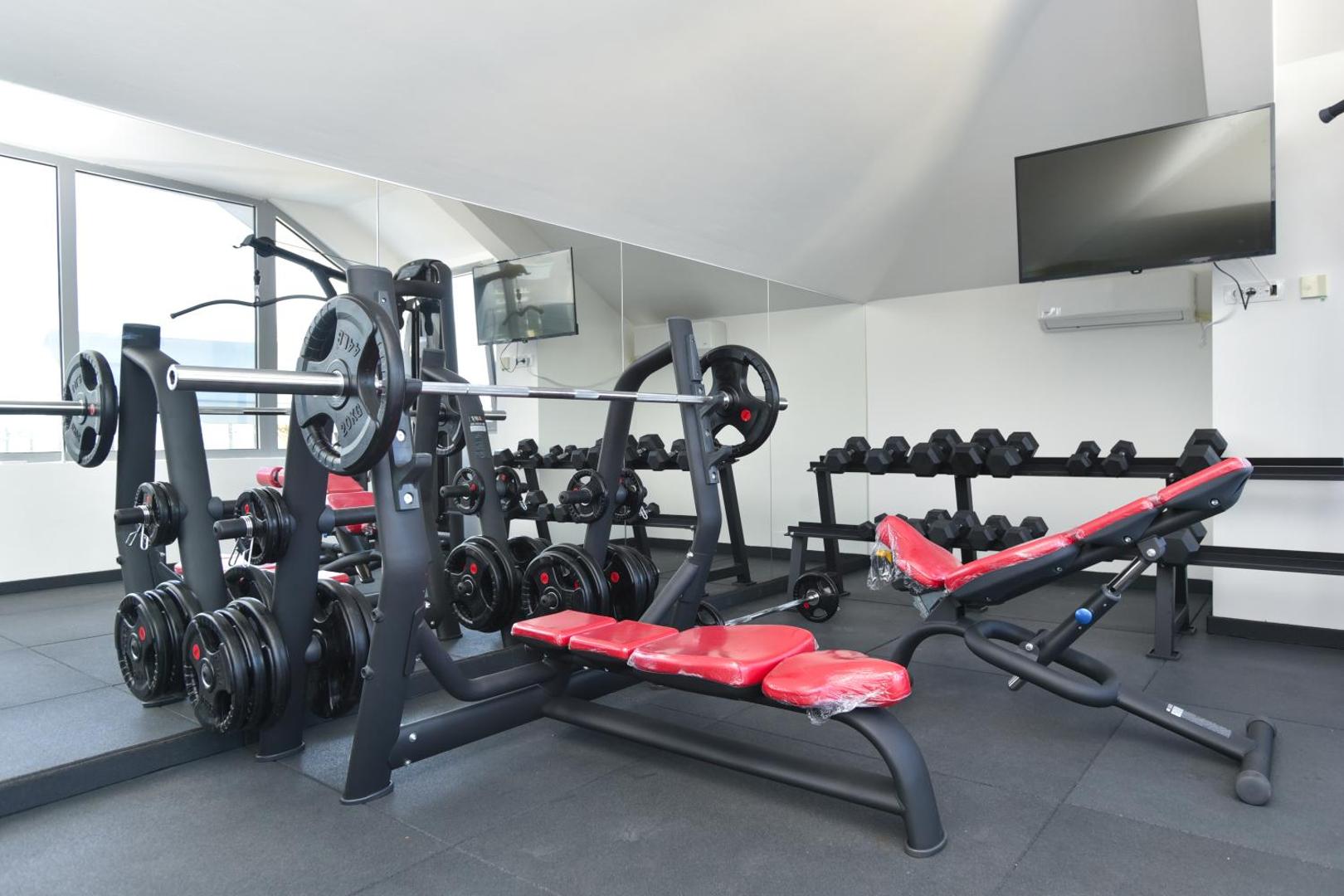 Viesnīcas La Mer fitness zāle ar moderniem trenažieriem, svariem, stieņiem un lieliem spoguļiem aktīvai atpūtai