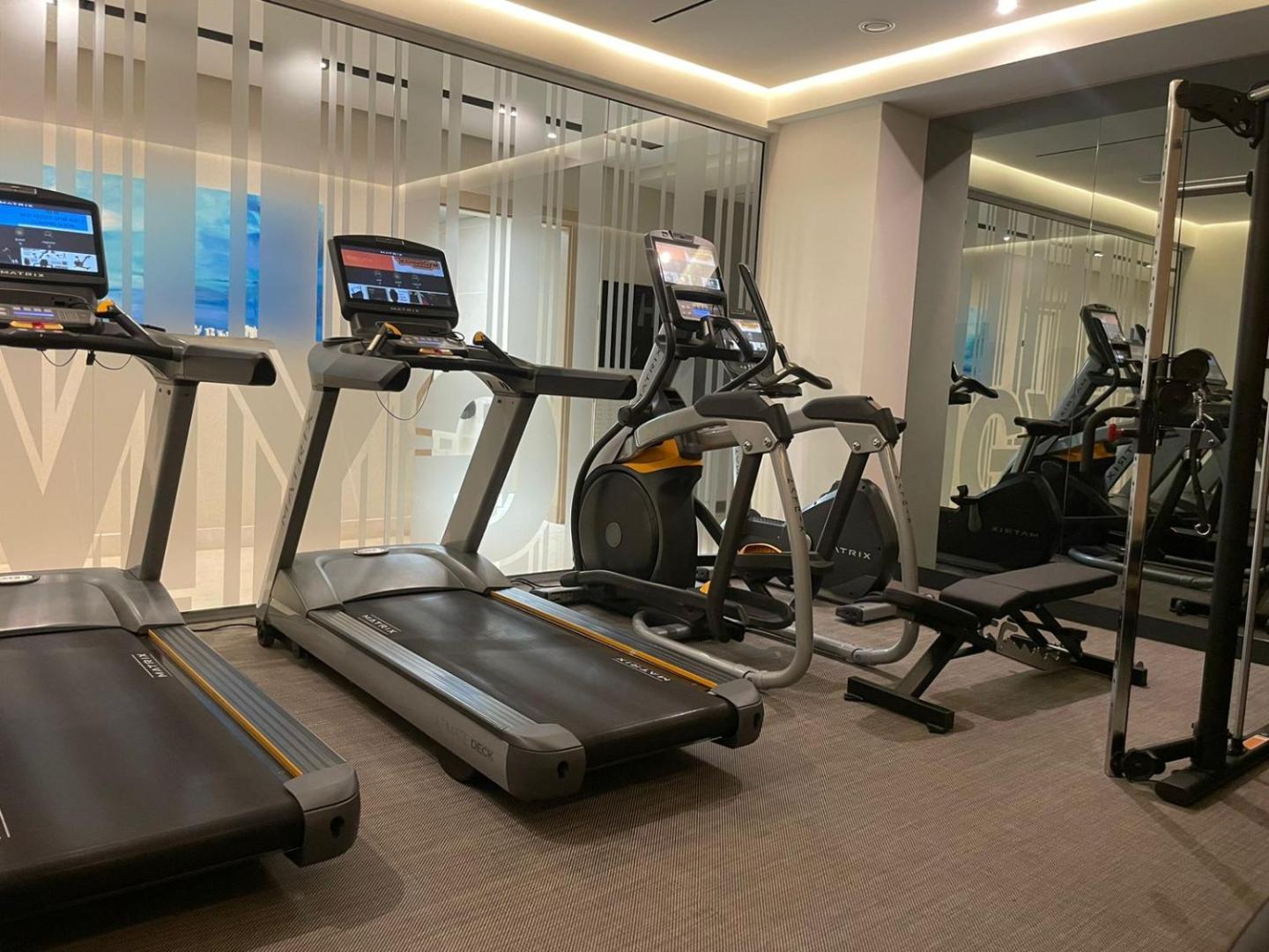Viesnīcas Katamare trenažieru zāle ar moderniem skrejceliņiem un fitnesa aprīkojumu Bečiči kūrortā, Melnkalnē — gaišas telpas aktīvai atpūtai