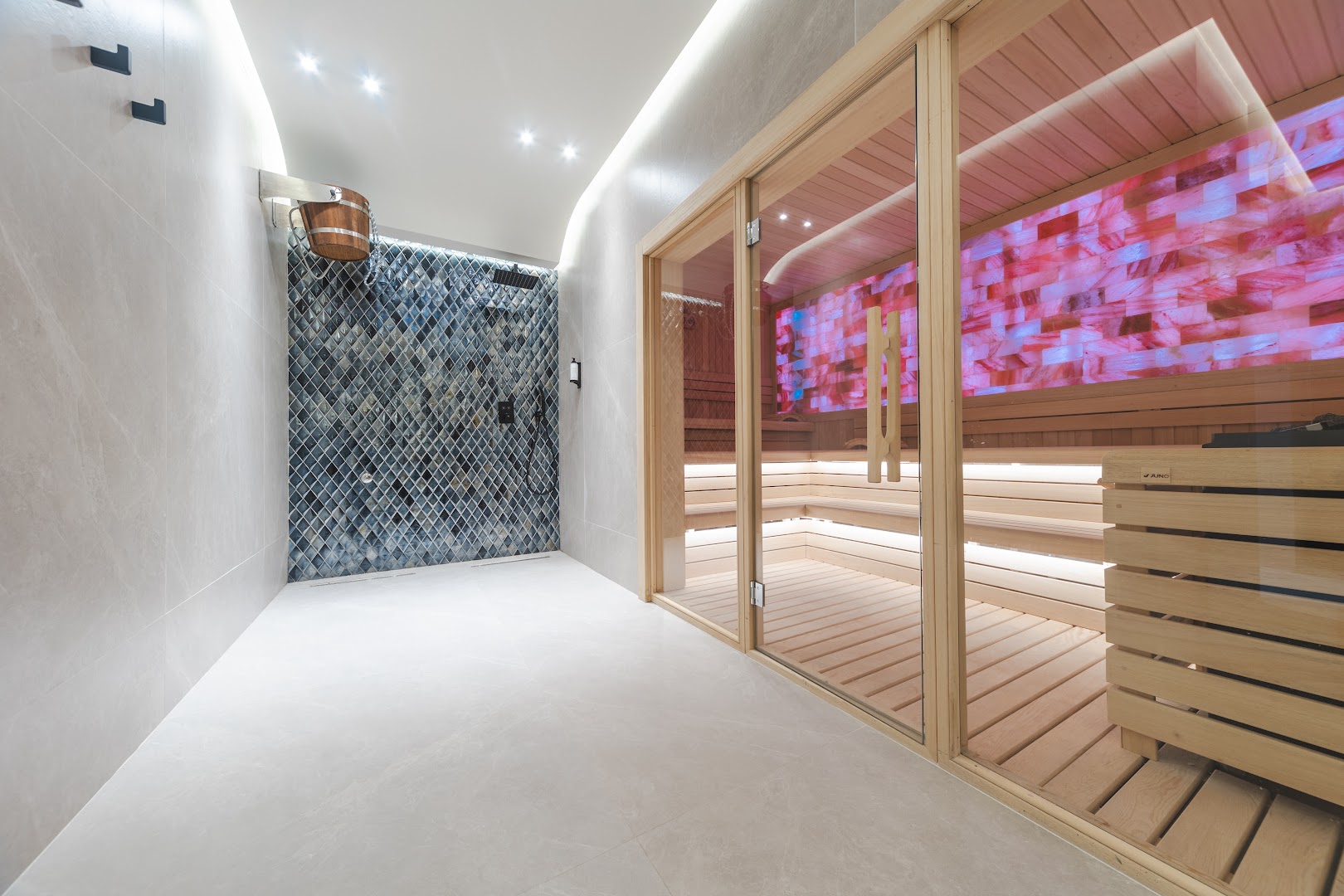Viesnīcas Katamare spa zona ar modernu saunu, kurā ir sāls sienas apgaismojums, un blakus esošu dušas telpu ar mozaīkas flīzēm