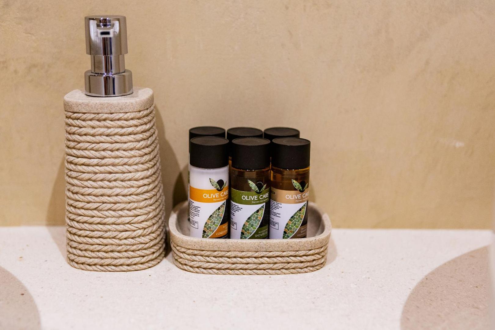 Viesnīcas Ruzmarin By Aycon vannasistabas piederumi Olive Care un šķidro ziepju dozators — kvalitatīva kosmētika viesu ērtībām Budvā.
