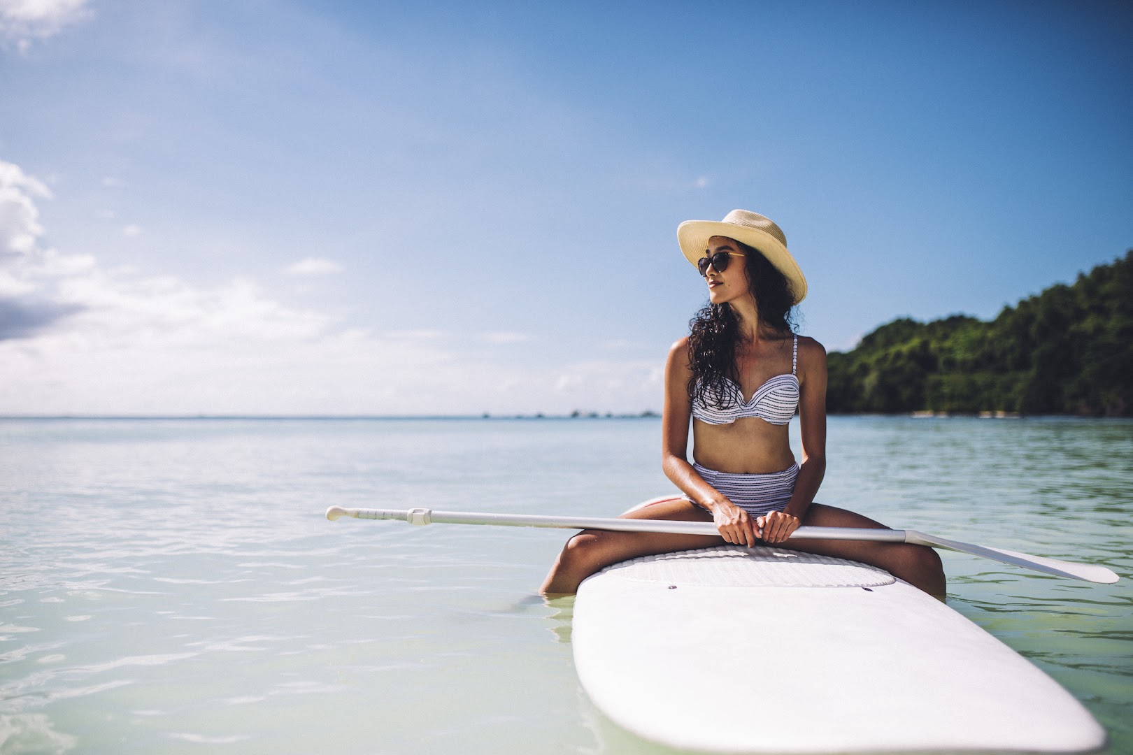 Club Med Seychelles viesnīcas viesis uz SUP dēļa tirkīzzilā Indijas okeāna ūdenī Seišelu salu piekrastē saulainā dienā