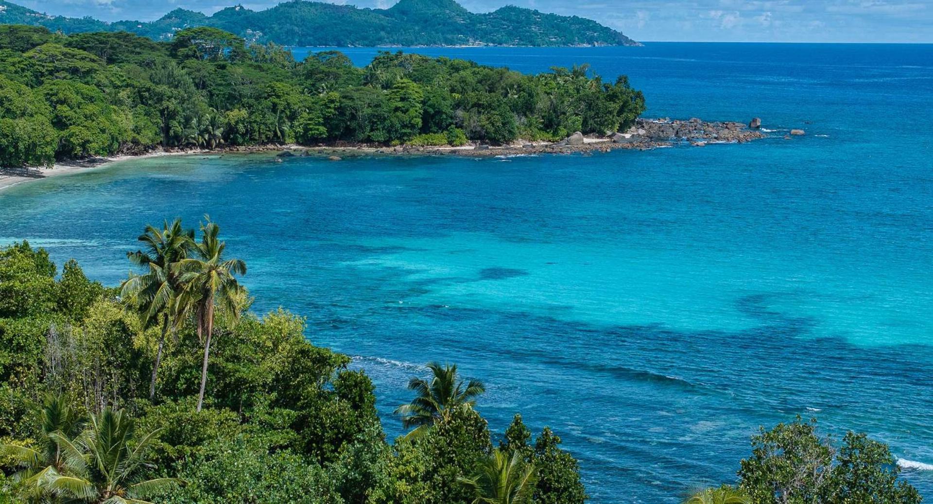 Avani+ Barbarons Seychelles Resort skats no augšas uz tirkīzzilo okeāna līci, palmu ieskautu piekrasti un blakus esošajām salām.