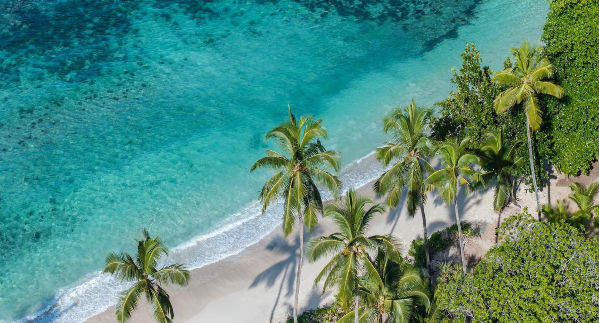 Aerofoto skats uz Avani+ Barbarons Seychelles privāto pludmali Seišelu salās — tirkīza krāsas okeāna ūdens, baltas smiltis un slaidas palmas