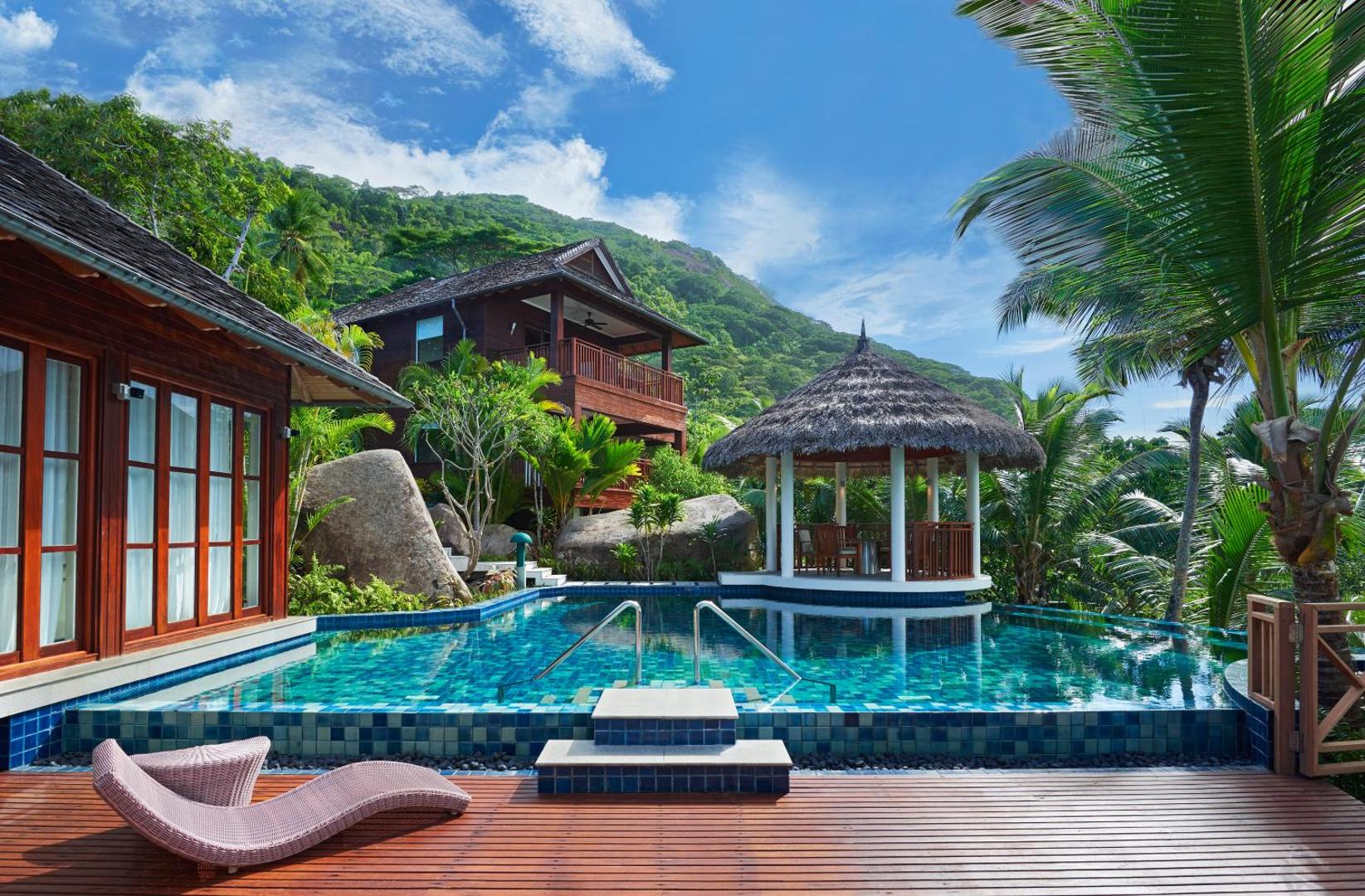 NIVA Labriz Seychelles kūrorta āra baseins ar koka terasi, sauļošanās krēsliem un tradicionālu lapeni tropu dārza un kalnu ielokā