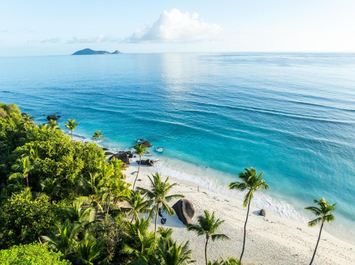 Aerofoto skats uz NIVA Labriz Seychelles balto smilšu pludmali, tirkīza ūdeni un zaļojošām palmām piekrastē