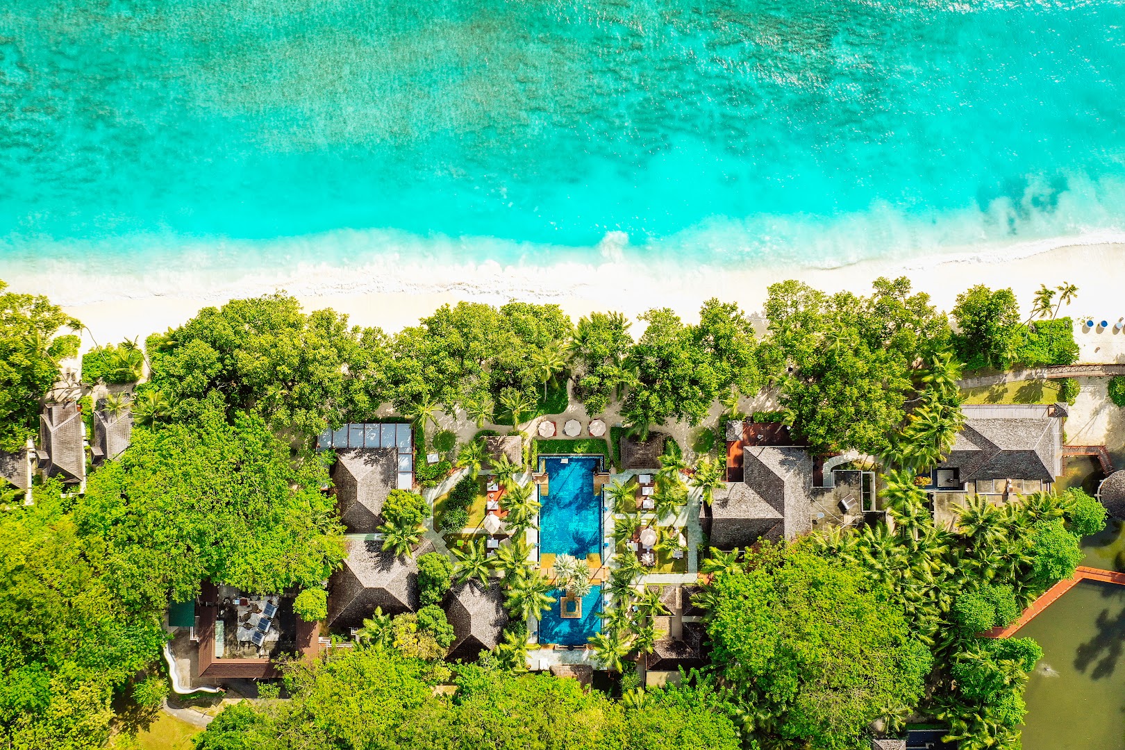 NIVA Labriz Seychelles kūrorta panorāmas skats no augšas uz baseinu, pludmali un tirkīzzilo okeānu saulainā dienā