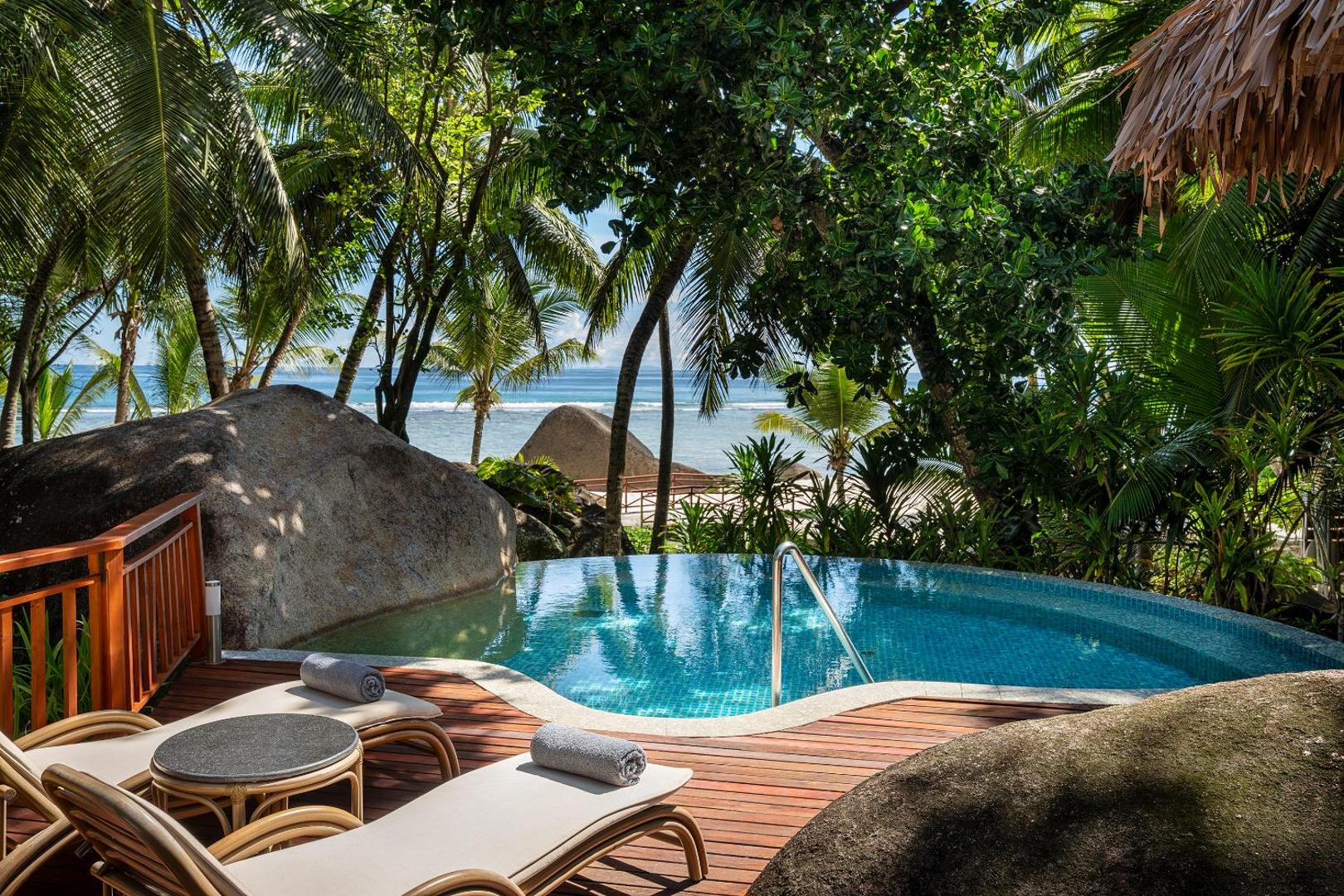 NIVA Labriz Seychelles neliels baseins piekrastē ar skatu uz okeānu, ko ieskauj granīta akmeņi, palmas un sauļošanās krēsli