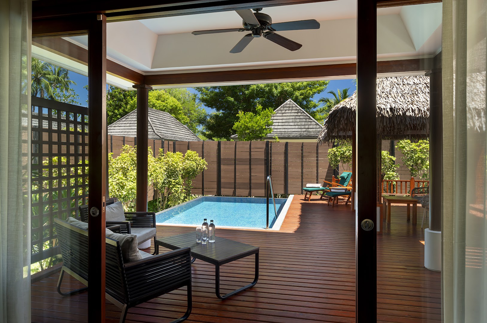 NIVA Labriz Seychelles villas terase ar atpūtas mēbelēm un nelielu baseinu, ko ieskauj zaļumi un koka žogs