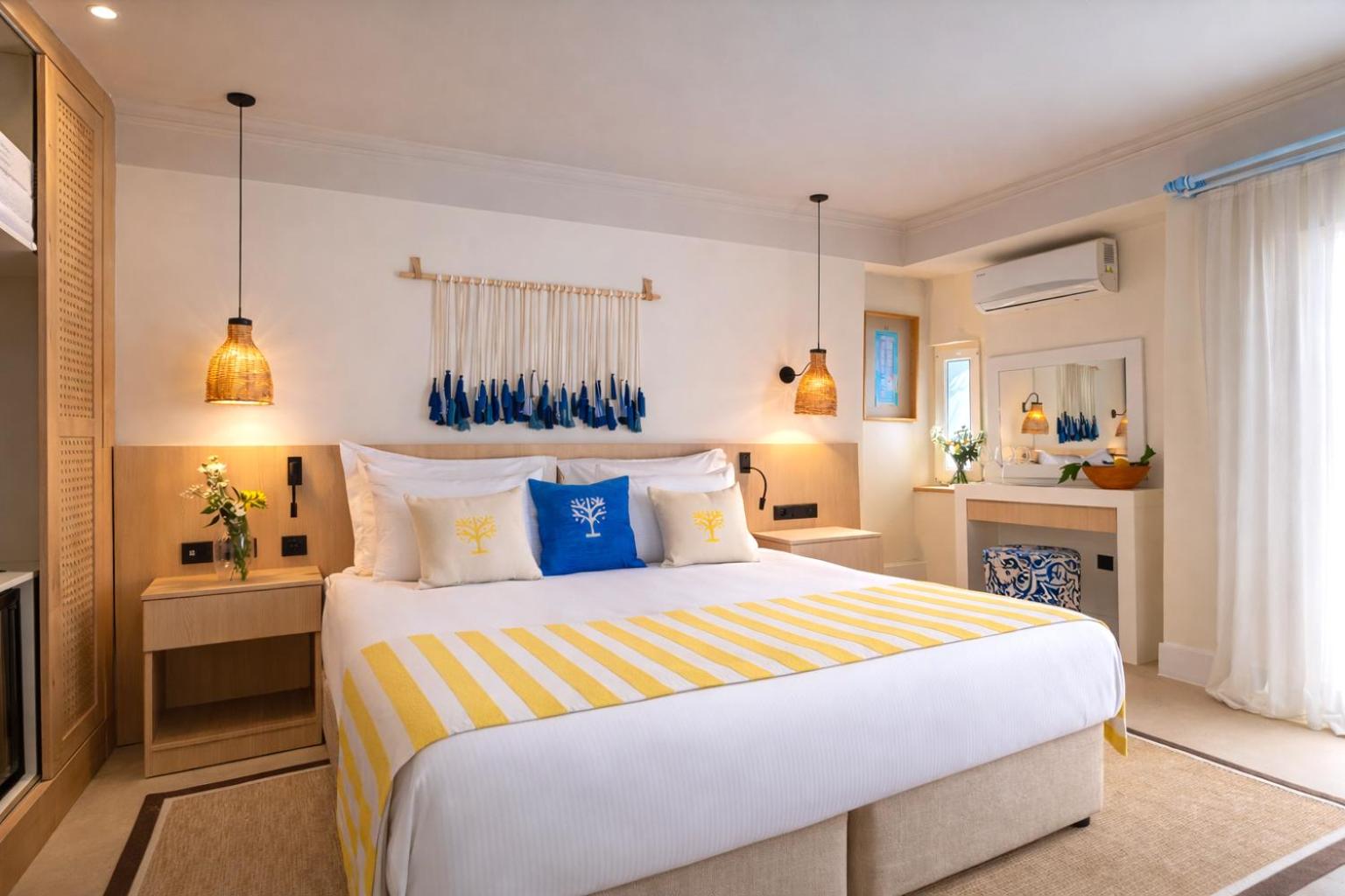 Baska Resort Bodrum gaišs divvietīgs numurs ar dzelteniem un ziliem akcentiem, pītiem gaismekļiem un makramē sienas dekoru Bodrumas piekrastē
