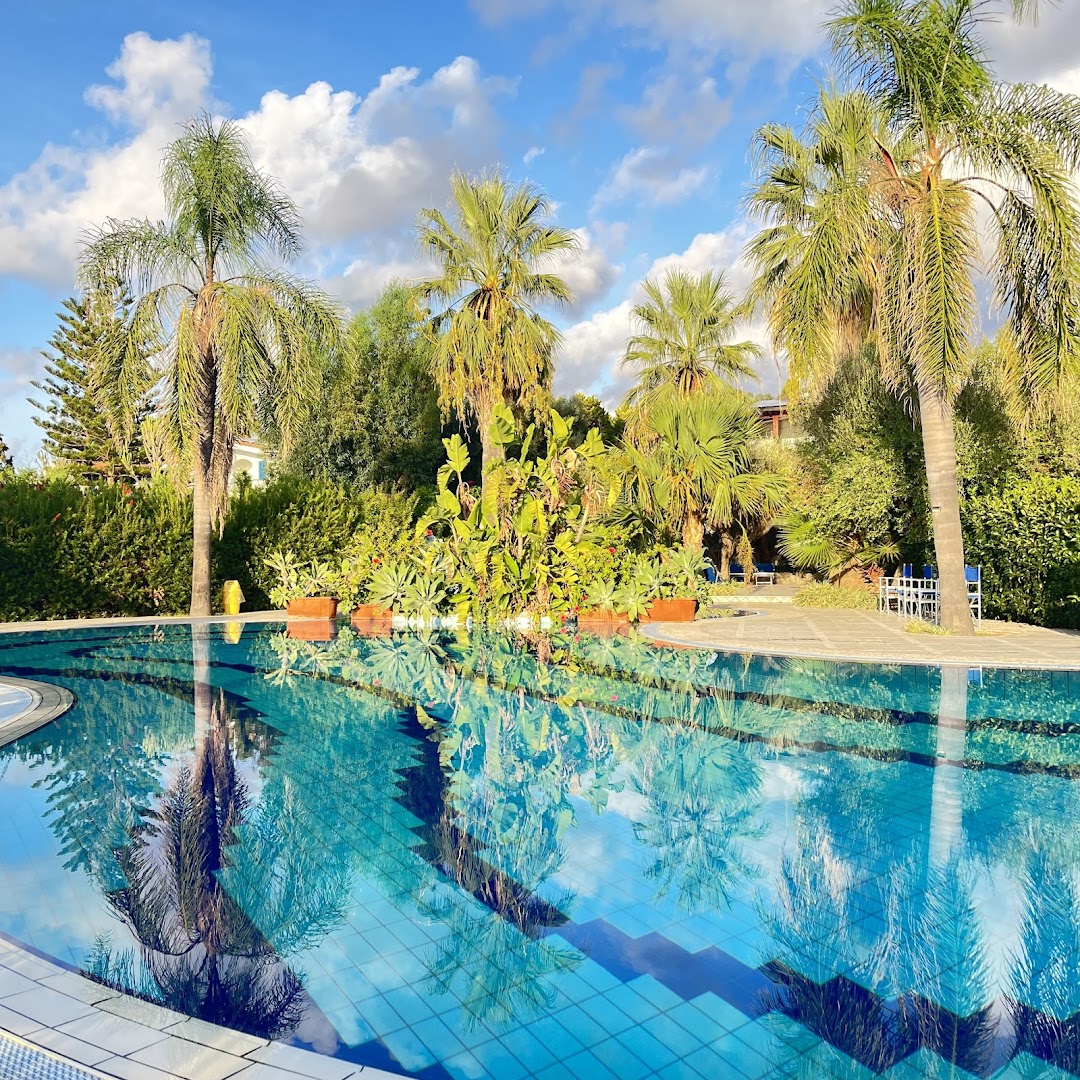 Tonicello Resort & Spa baseina spoguļattēls ar palmām un tropiskiem augiem saulainā dienā Kalabrijas reģionā
