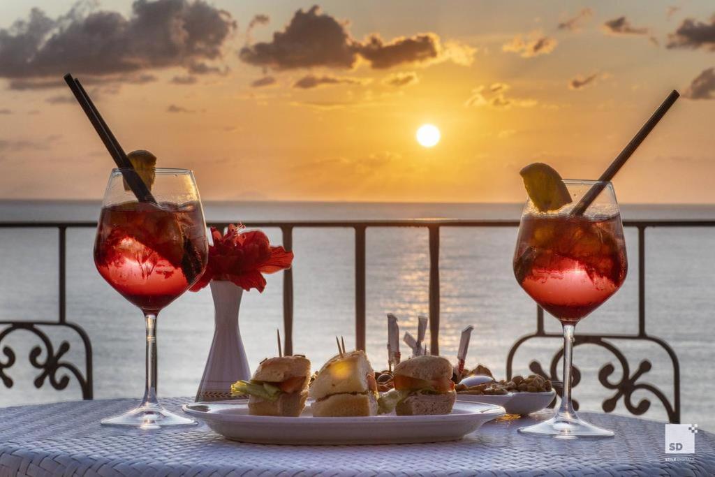 Saulrieta skats no Tonicello Resort & Spa terases ar kokteiļiem un uzkodām uz galda pie jūras