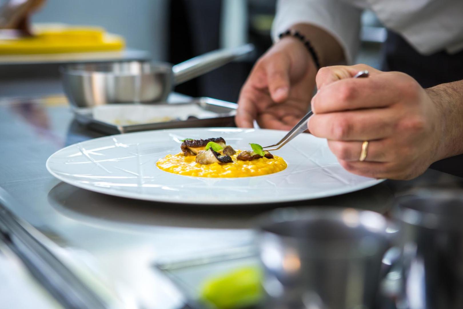 Galia Luxury Resort šefpavārs servē izsmalcinātu risoto ēdienu uz balta šķīvja viesnīcas restorānā